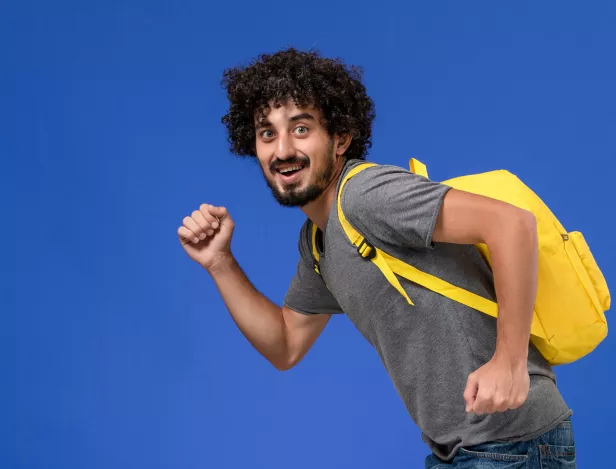 front-view-young-male-grey-t-shirt-wearing-yellow-backpack-smiling-running-blue-wall
